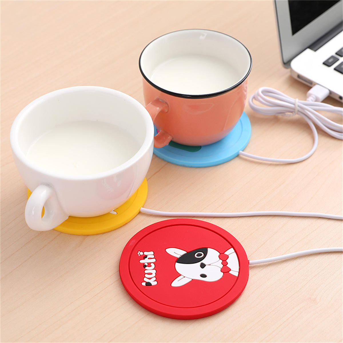 Zwei Tassen mit Milch auf bunten Untersetzern und ein roter Untersetzer mit Hundedesign. Ein Laptop im Hintergrund.