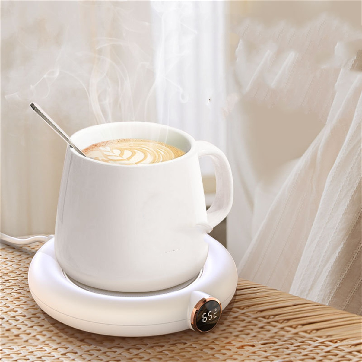 Eine weiße Tasse mit Kaffee und einem Löffel steht auf einem weißen beheizten Untersetzer. Dampf steigt auf.
