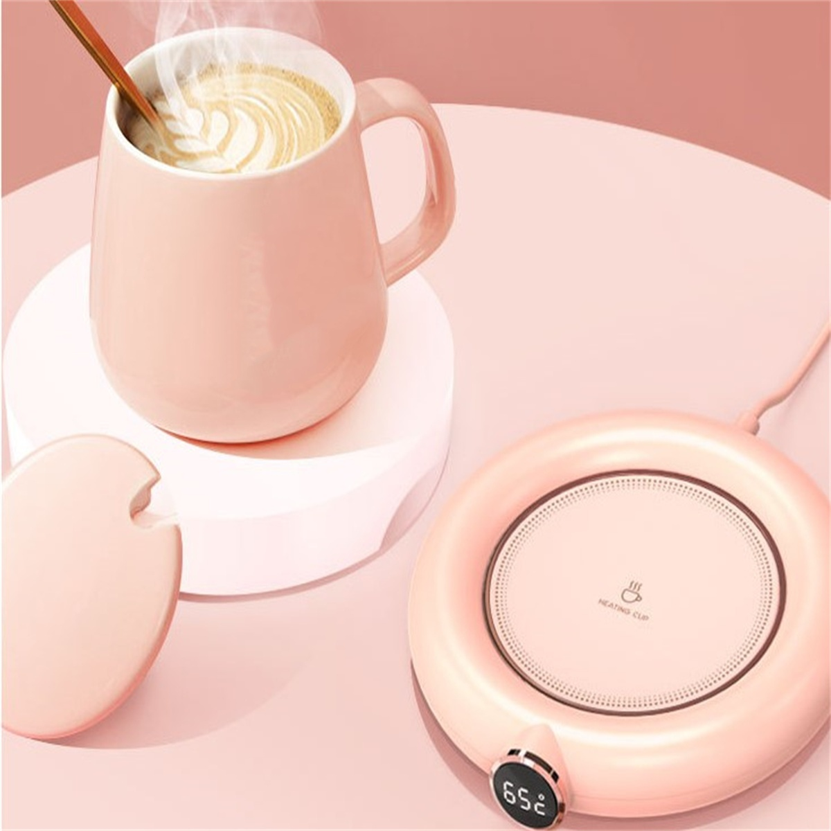 Ein rosa Becher mit einem Löffel steht auf einem weißen Ständer. Daneben steht eine rosa Heiztasse.
