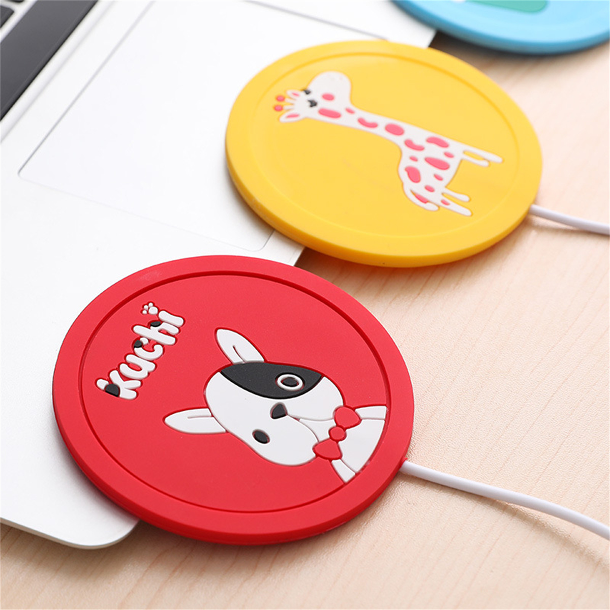 Laptop mit zwei bunten, runden Ladepads. Eines ist gelb mit einer Giraffe, das andere rot mit einem Hund.