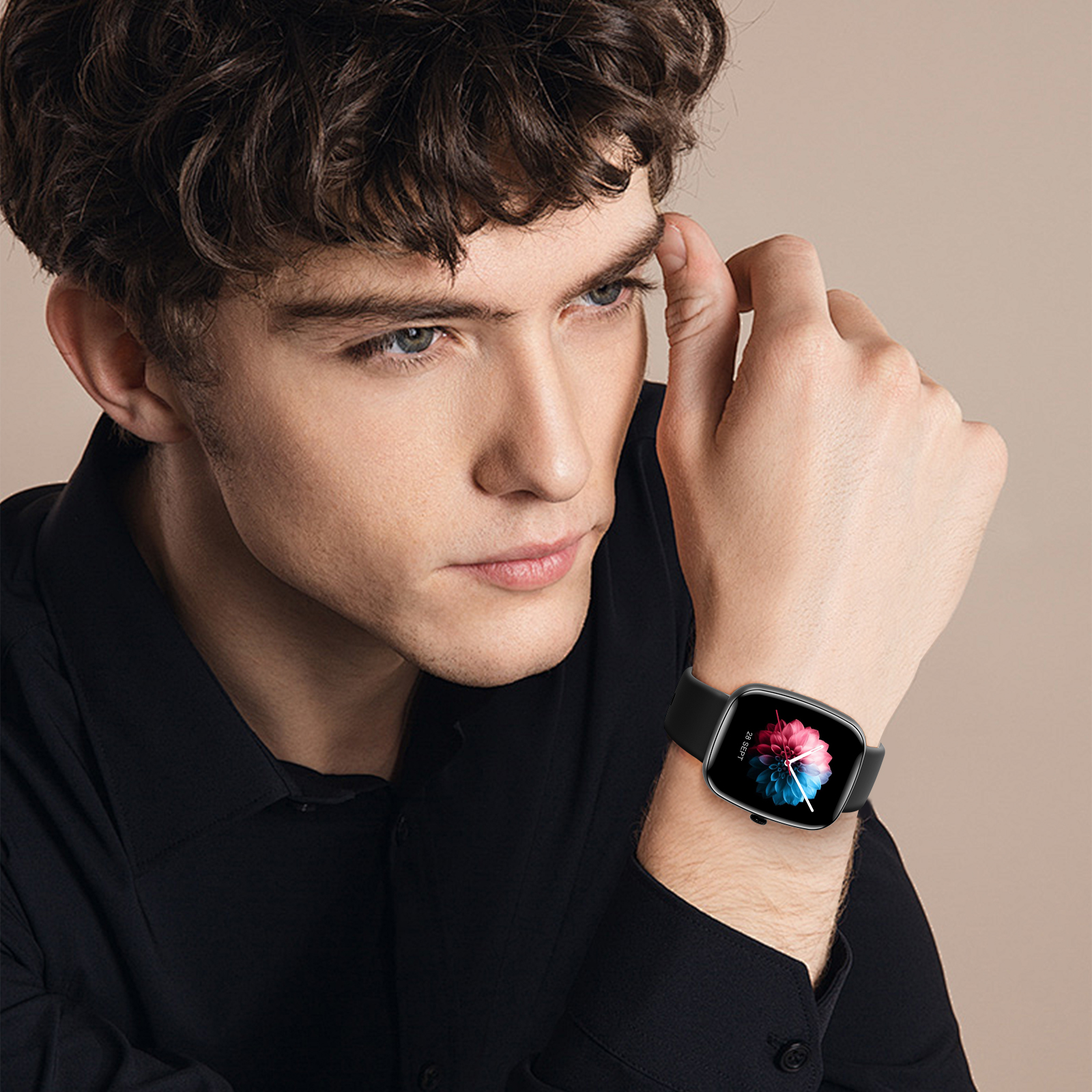 Mann trägt eine schwarze Smartwatch. Die Smartwatch hat ein farbenfrohes Display. Beigefarbener Hintergrund.