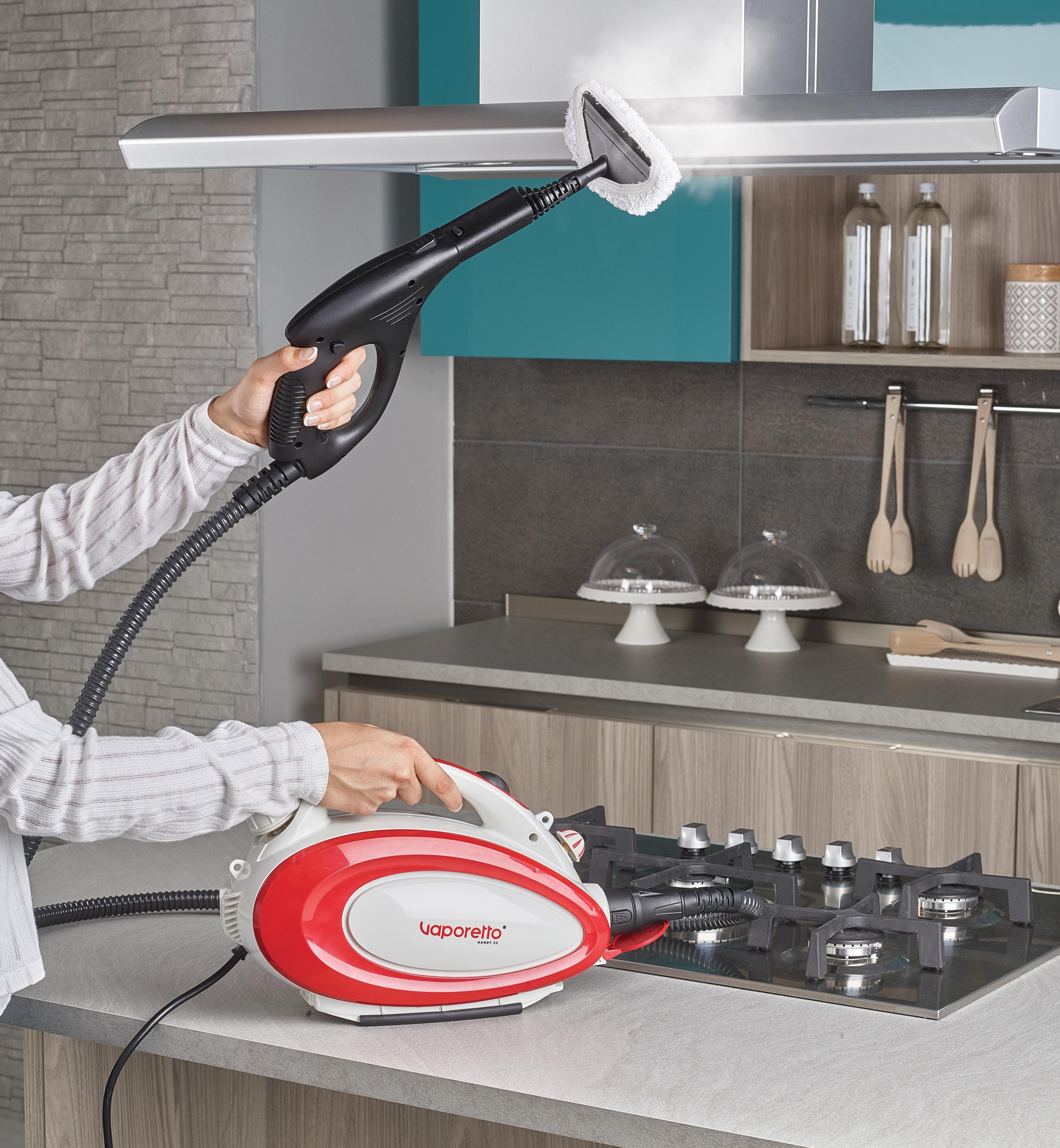 Osoba paruje blat kuchenny. Parowar jest czerwono-biały, otoczenie to kuchnia.