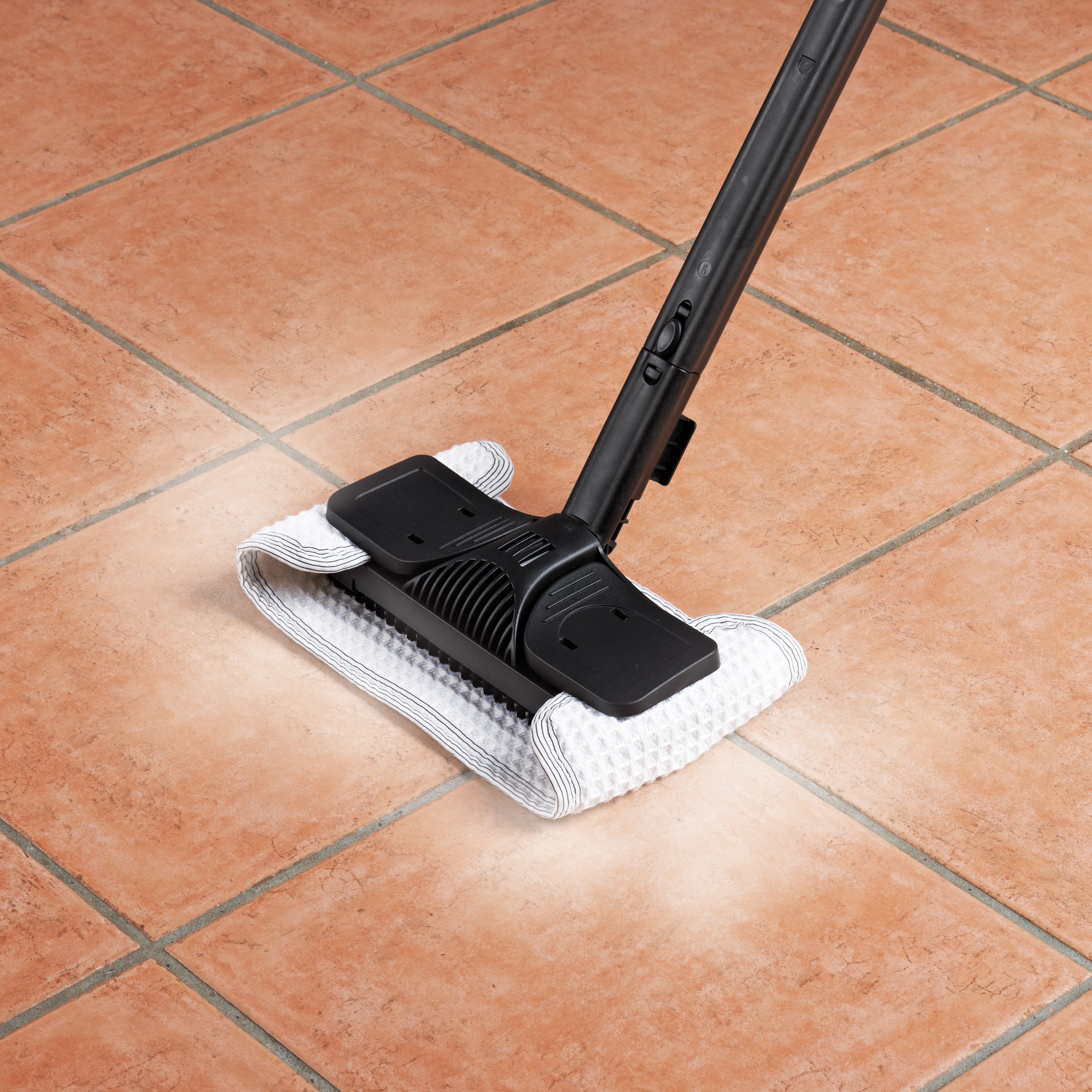 Głowica myjki parowej na kafelkach. Głowica jest czarna z białą i szarą nakładką czyszczącą.