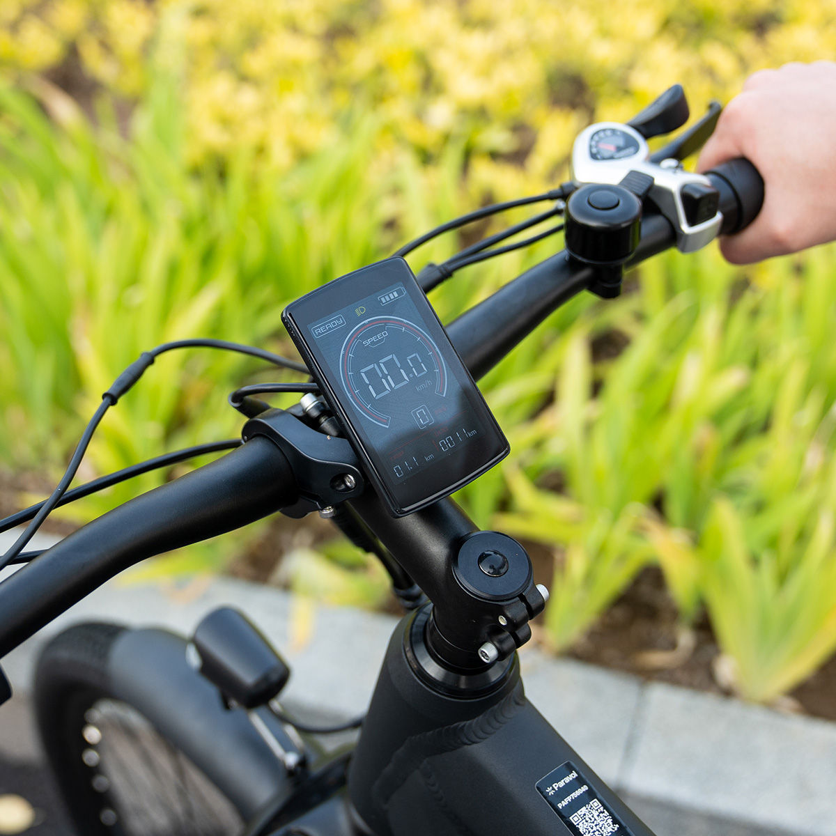 Ein schwarzer E-Bike-Lenker mit Display, das die Geschwindigkeit anzeigt, umgeben von Grün.