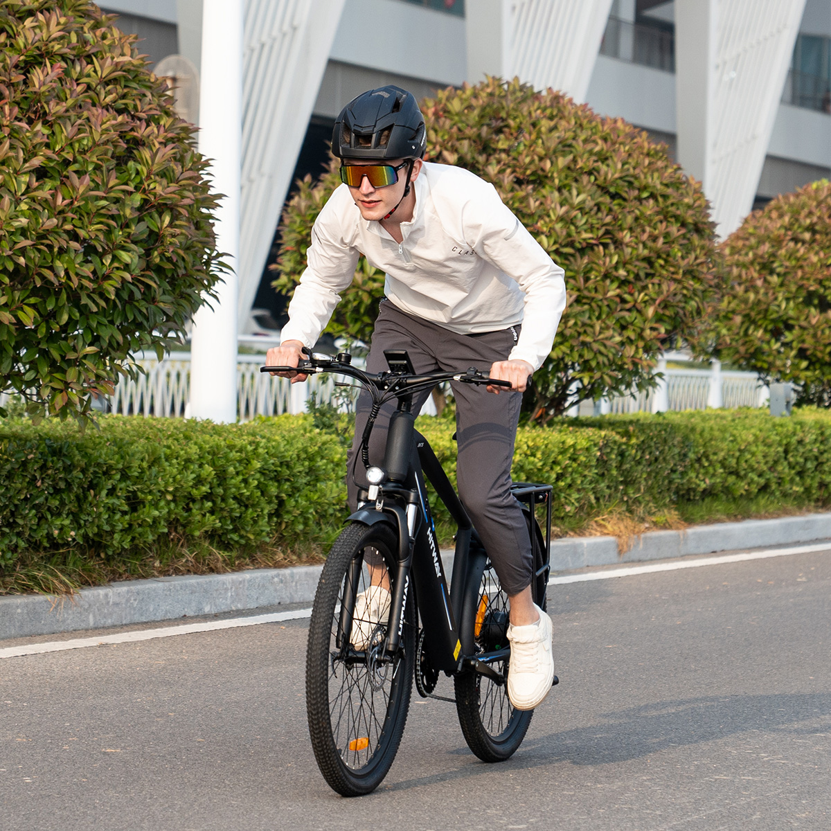 Uomo in bicicletta elettrica su strada, con casco e occhiali da sole.