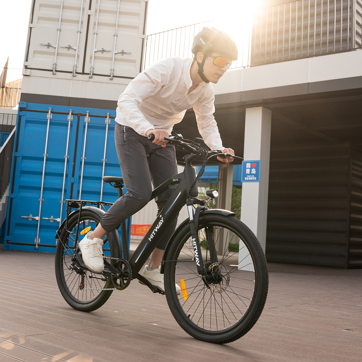 Mann fährt ein schwarzes HITWAY Elektrofahrrad auf einer Holzoberfläche.