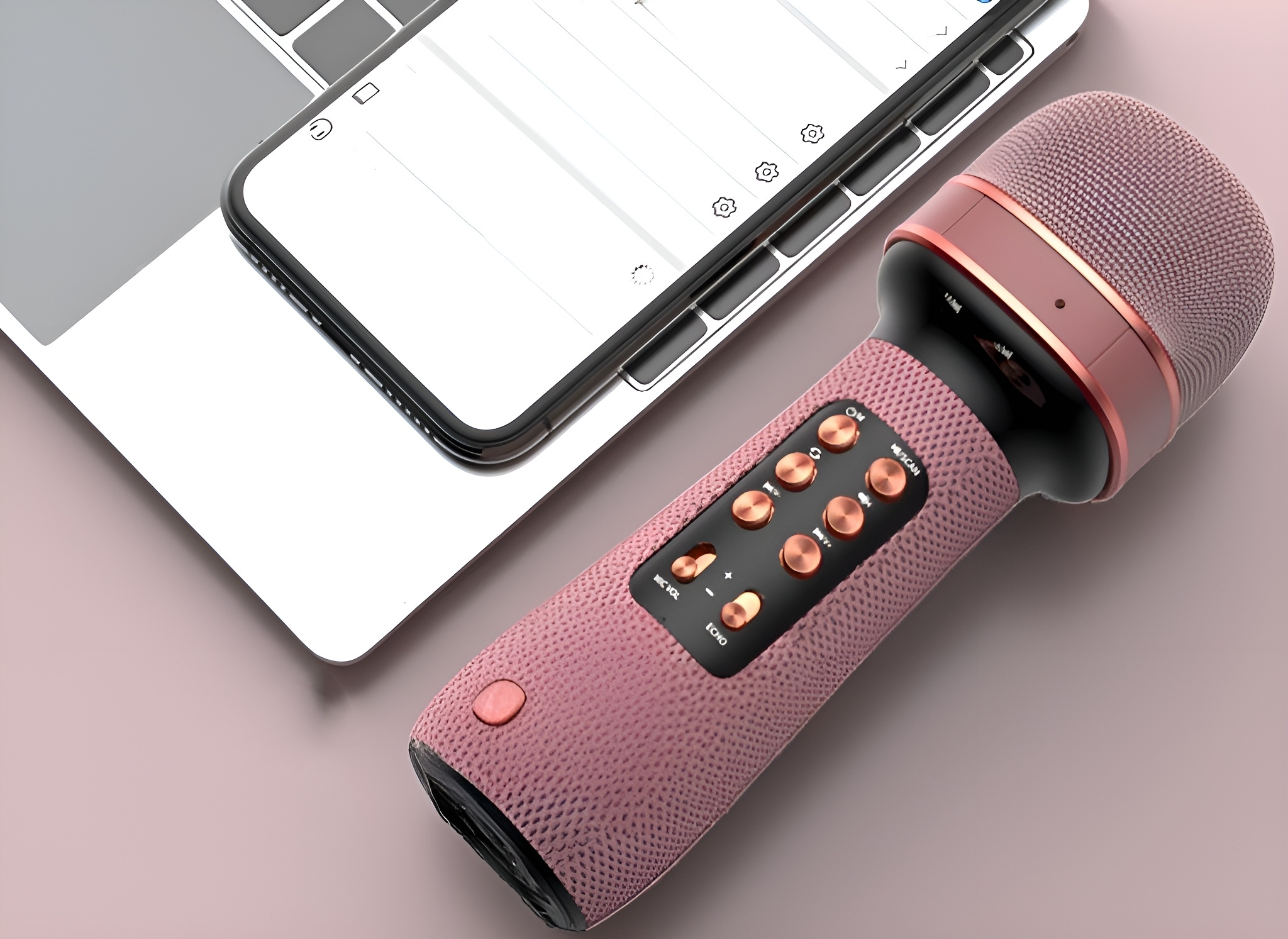 Ein rosa Mikrofon mit goldenen Akzenten und ein Telefon auf einem Laptop.