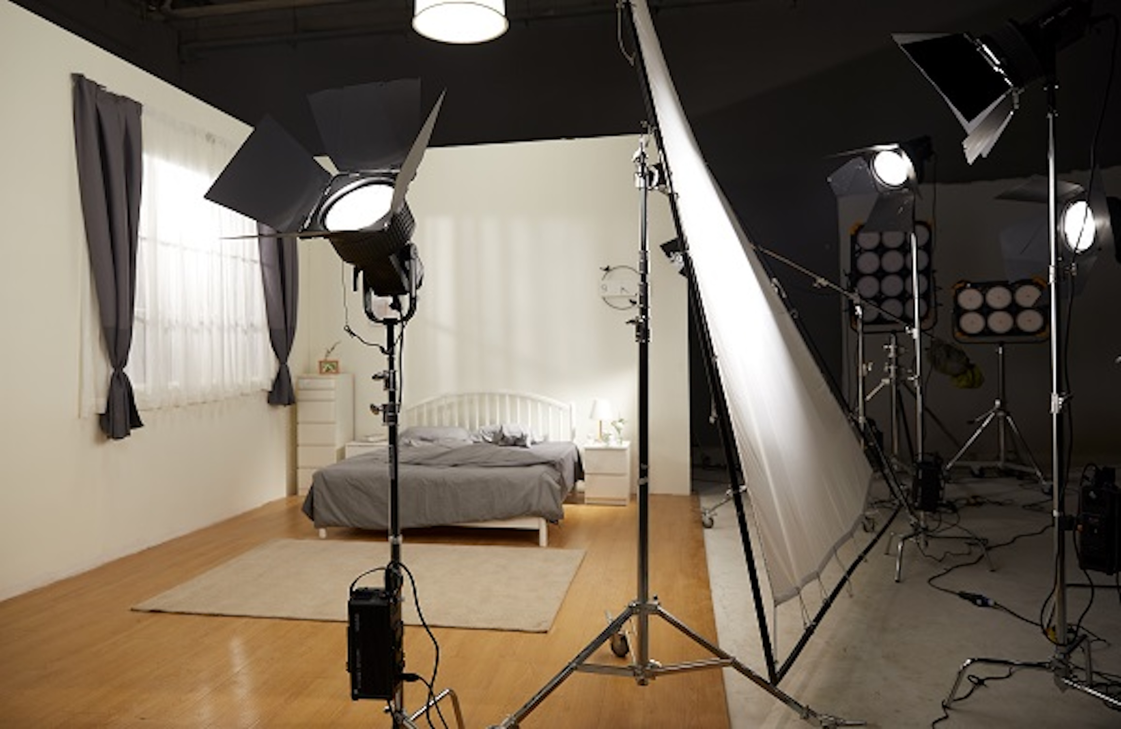 Ein Schlafzimmer mit Bett, Lichtern und Vorhängen. Ein Filmset mit Beleuchtungsausrüstung.