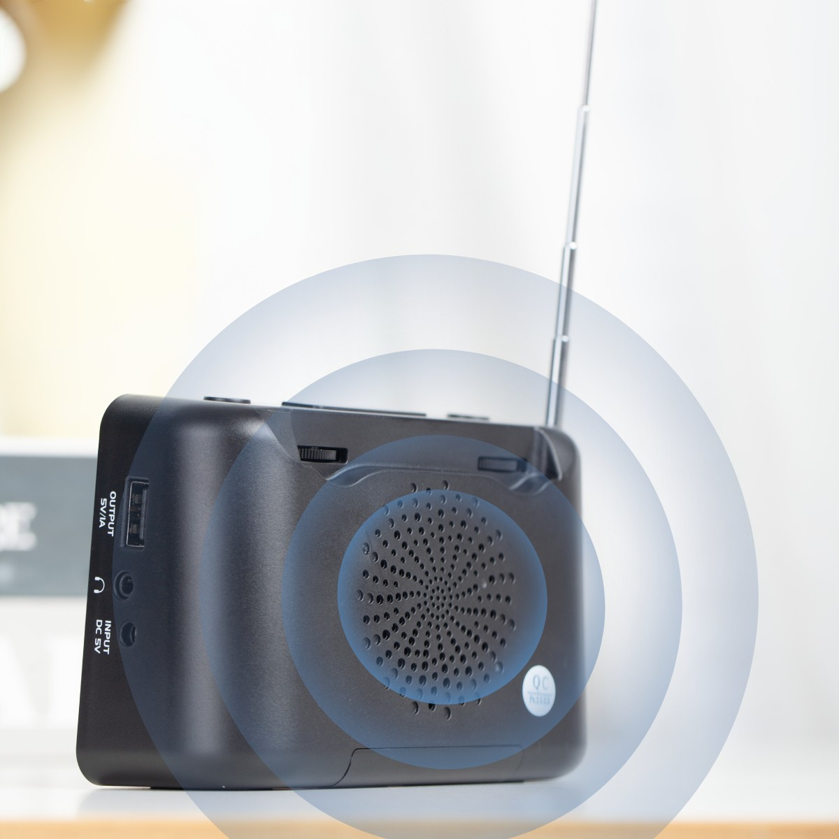 Ein schwarzes tragbares Radio mit einer Metallantenne. Blaue Schallwellen gehen vom Lautsprecher aus.