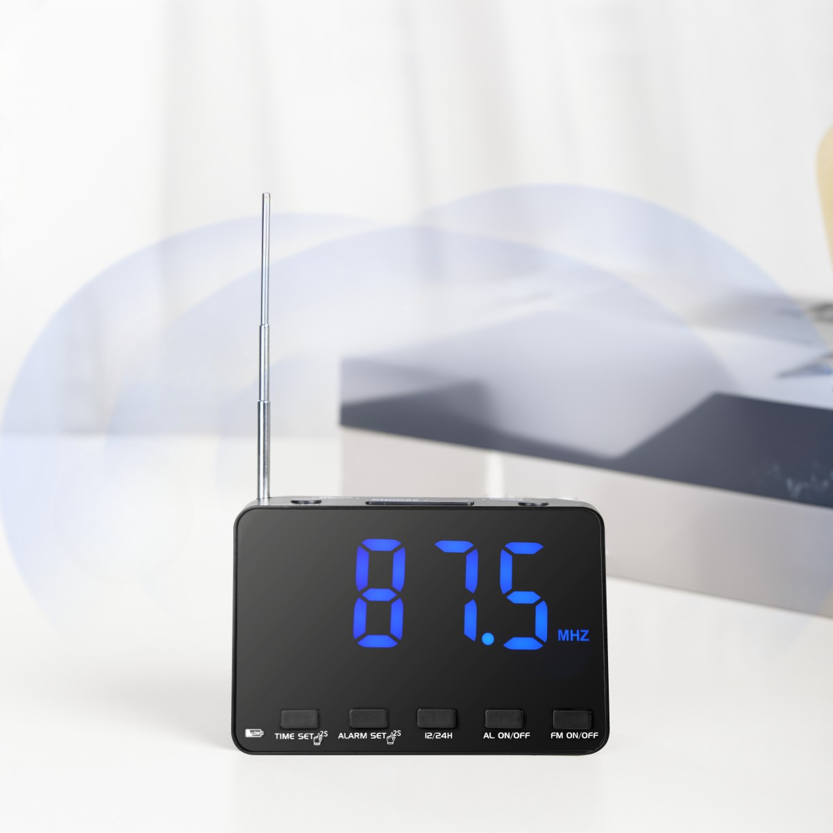 Schwarzes digitales Radiowecker mit 87,5 MHz. Eine silberne Antenne und weiße Oberfläche.