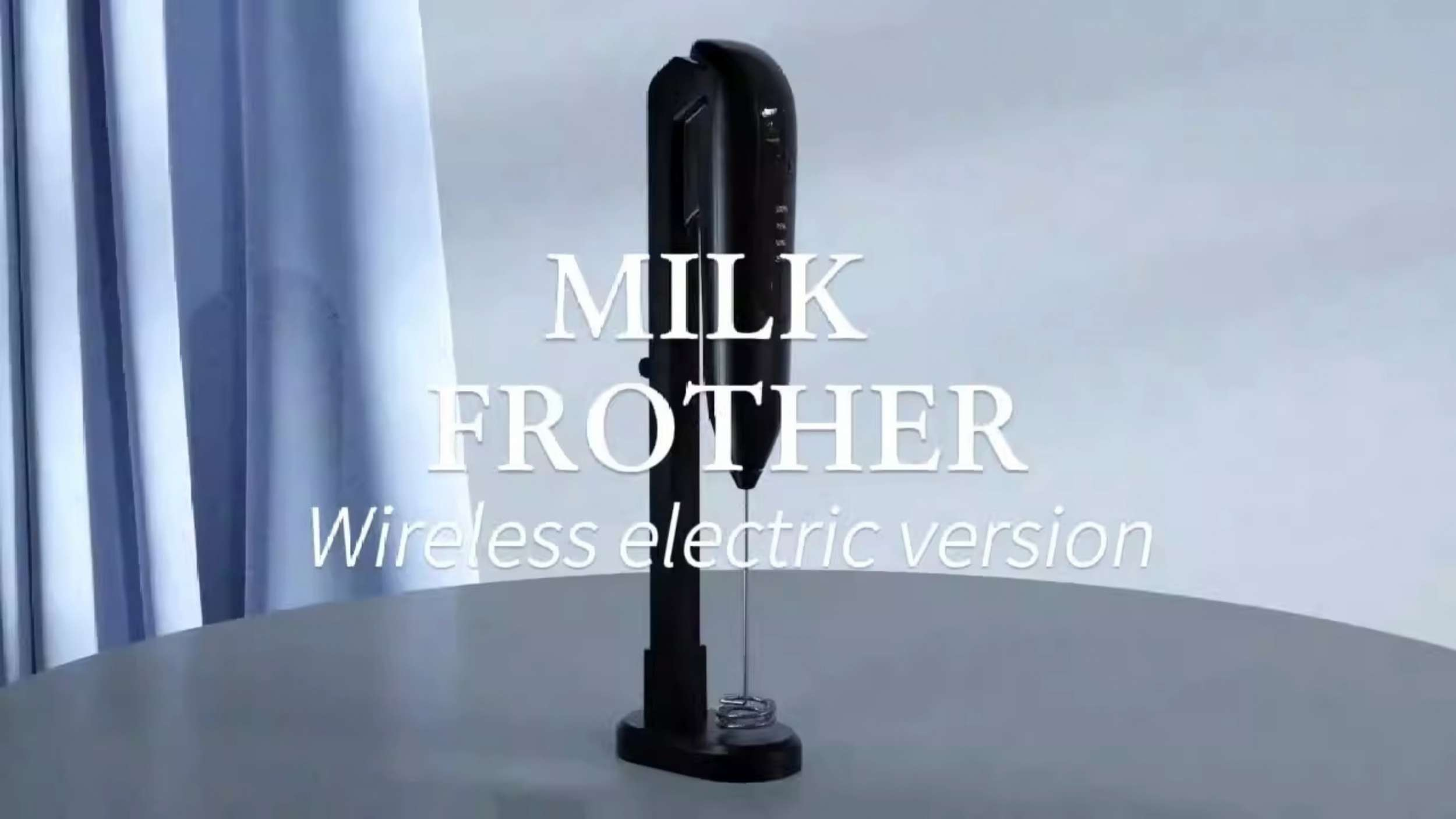 Schwarzer Milchaufschäumer steht auf einem Tisch, darüber steht 'MILK FROTHER'.