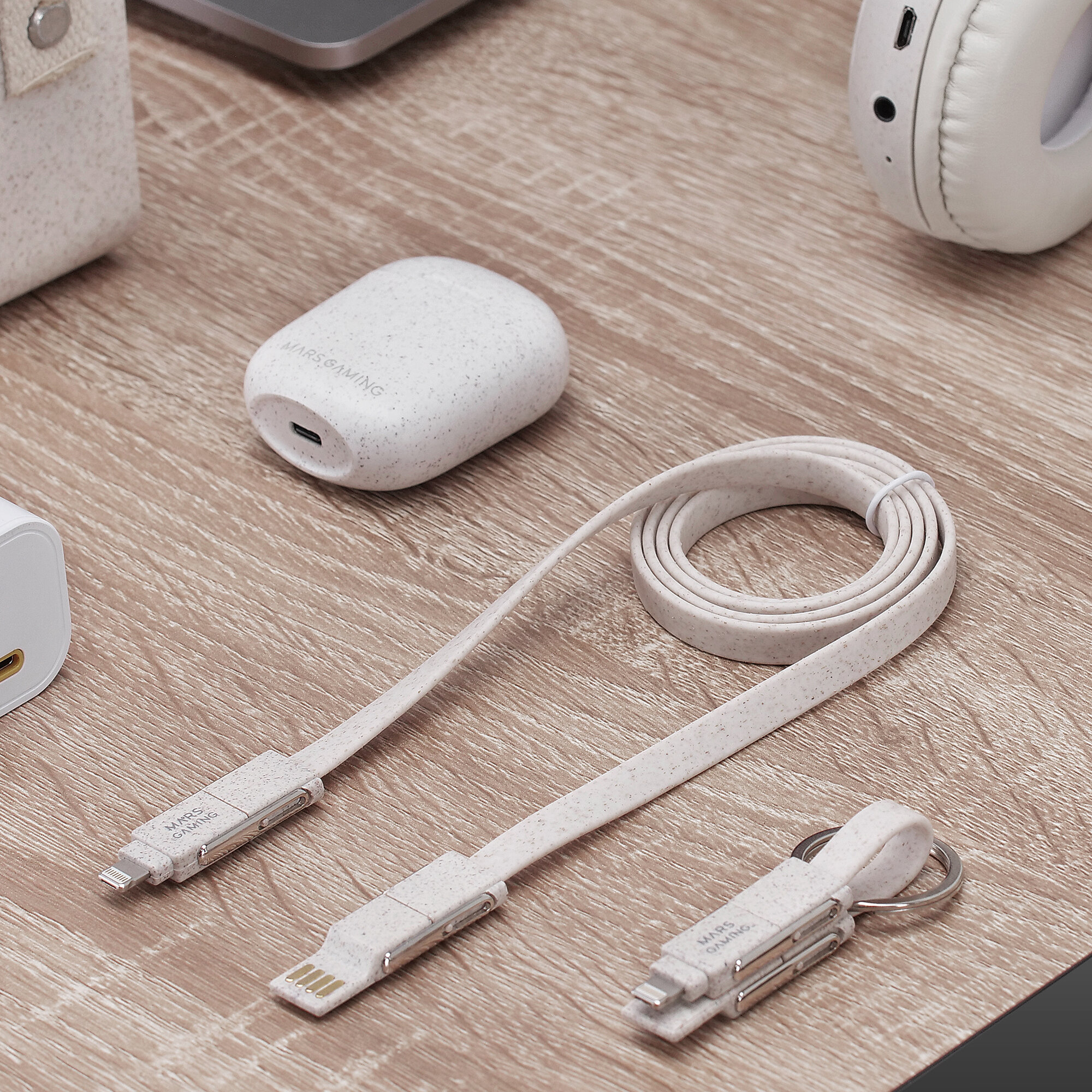 White charging cables and accessories on a wooden table. A white headset is in the background.