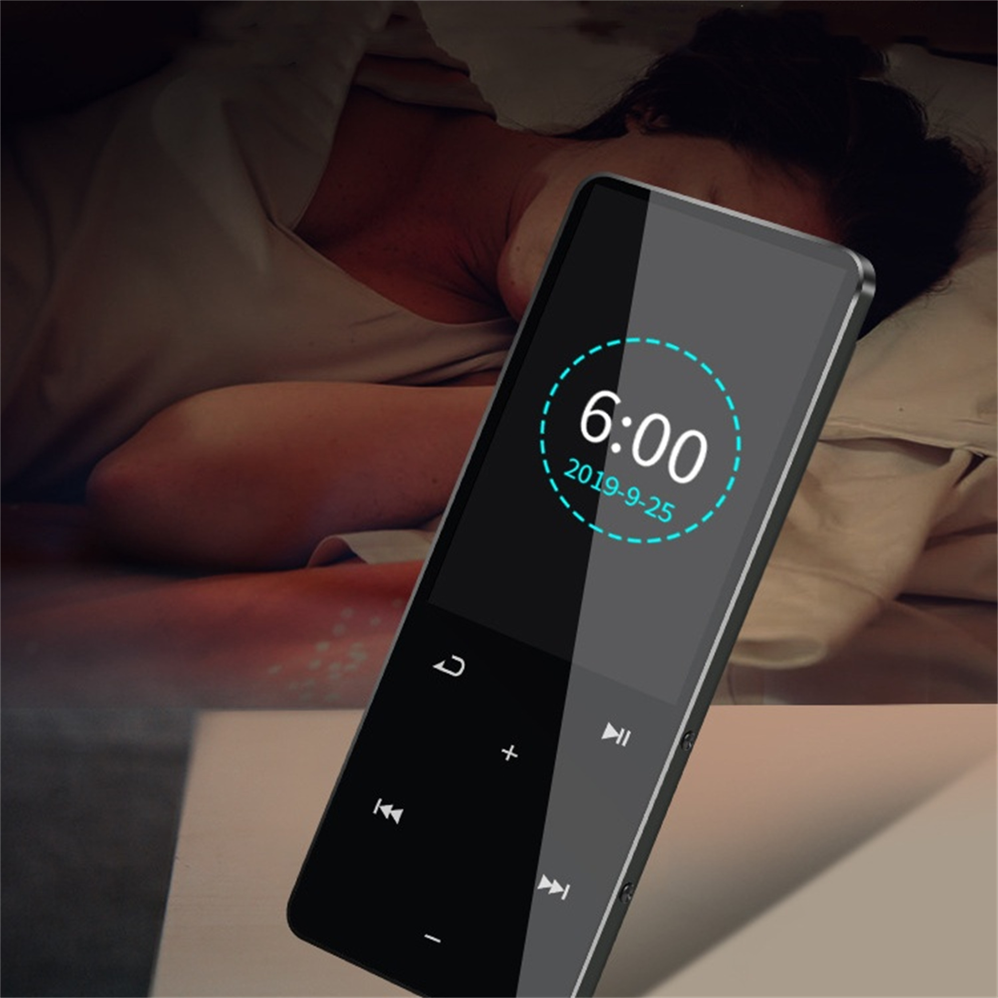 Schwarzer digitaler Musikplayer mit Bildschirm. Zeigt Uhrzeit und Datum. Eine Person liegt im Bett.