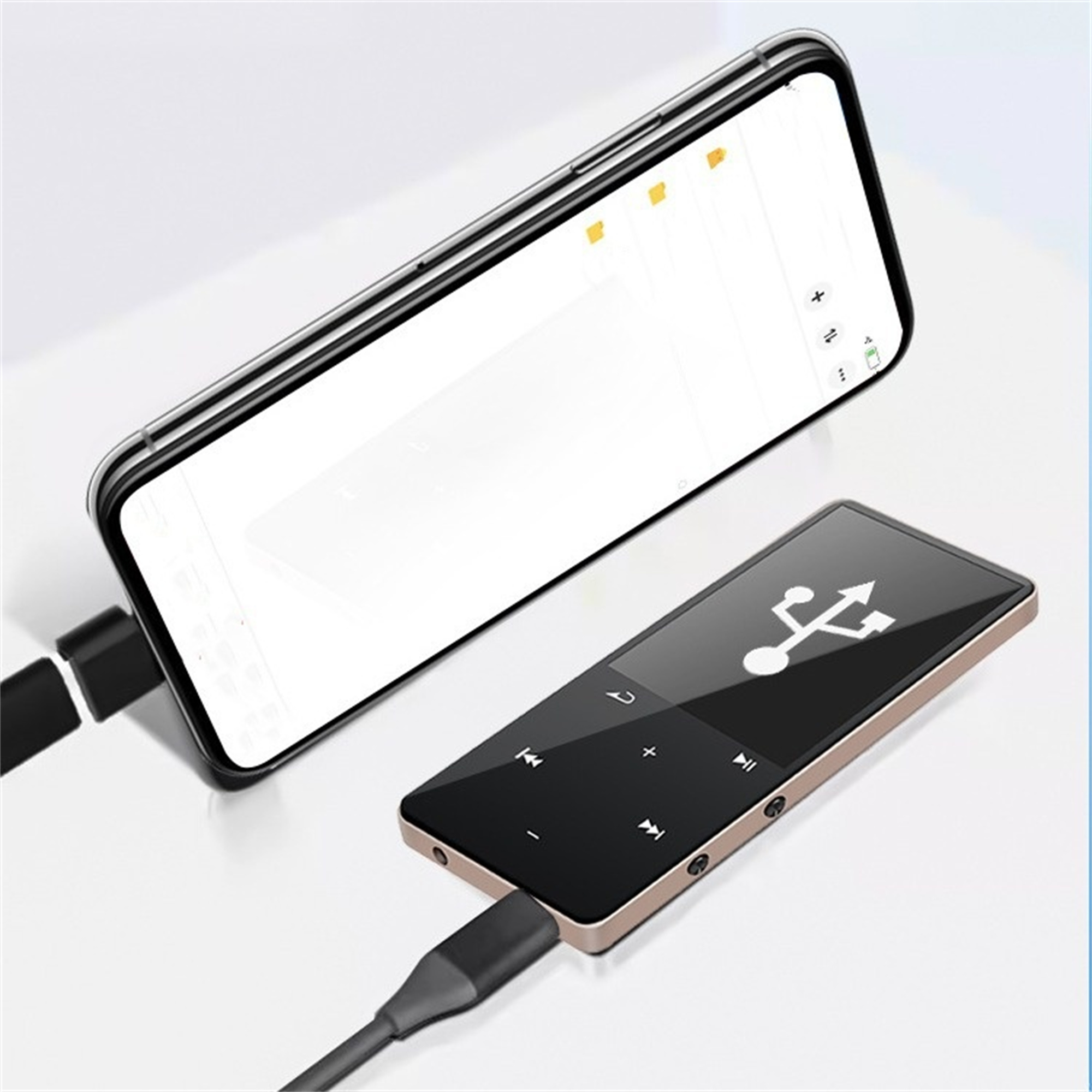 Schwarzes Telefon, verbunden mit einem goldenen Musikplayer über ein schwarzes Kabel auf weißer Oberfläche.