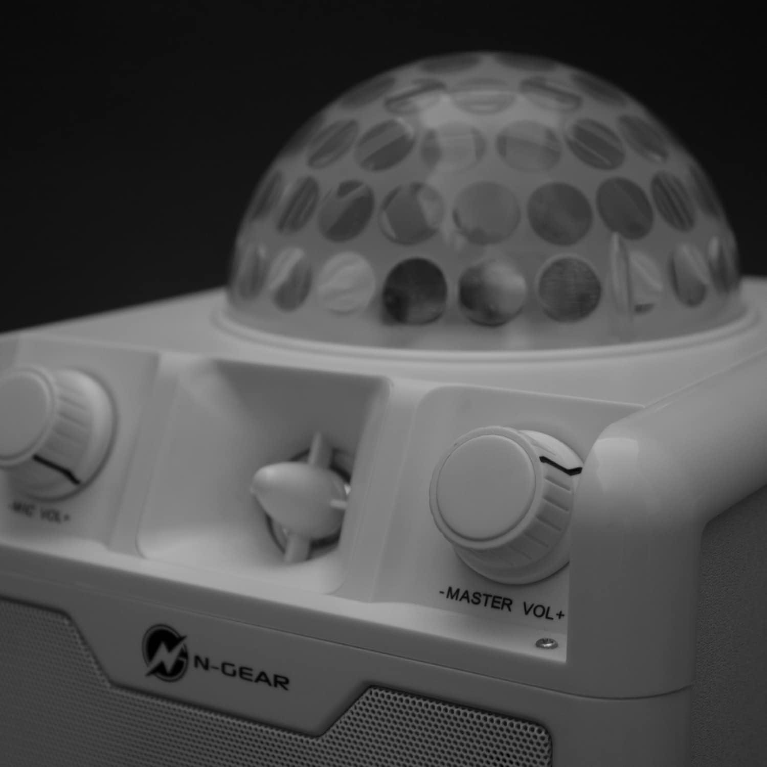 Un primo piano in bianco e nero di un altoparlante con controlli del volume e una luce a sfera da discoteca sopra.