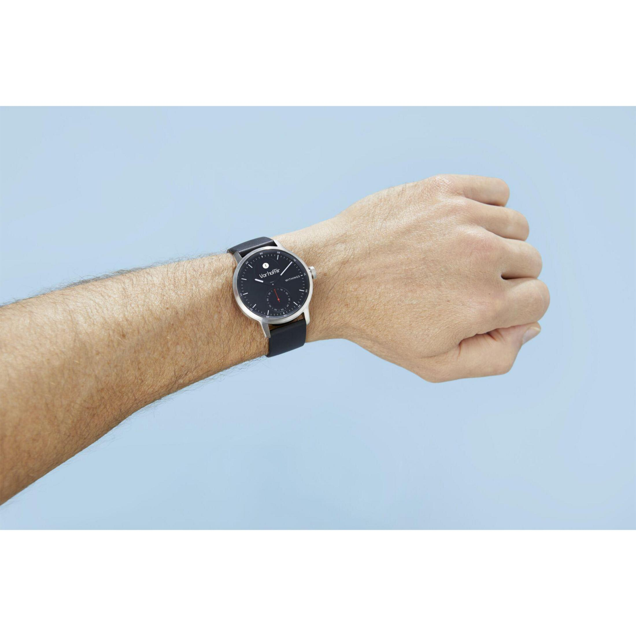 Handgelenk einer Person mit schwarzer Uhr, zeigt die Zeit, und blauer Hintergrund.