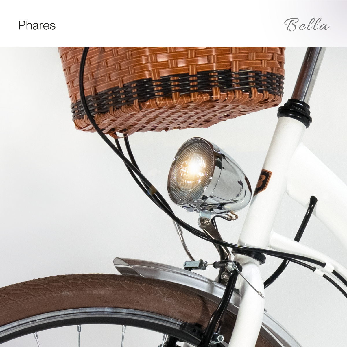 Nahaufnahme eines weißen Fahrrades mit Weidenkorb, Scheinwerfer und Text Phares Bella.