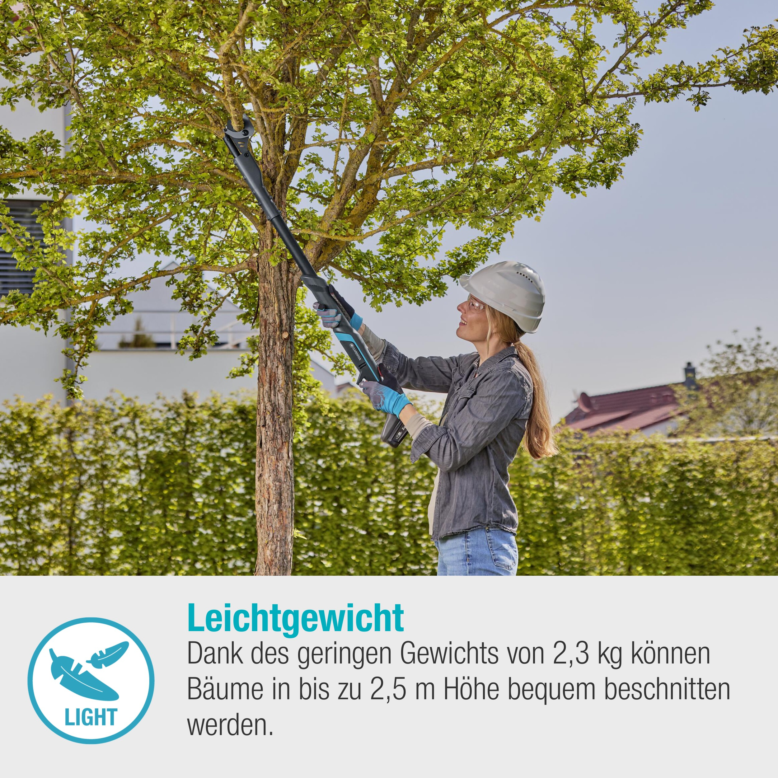 Frau mit Helm beschneidet Baum mit elektrischer Säge, grüne Büsche im Hintergrund.
