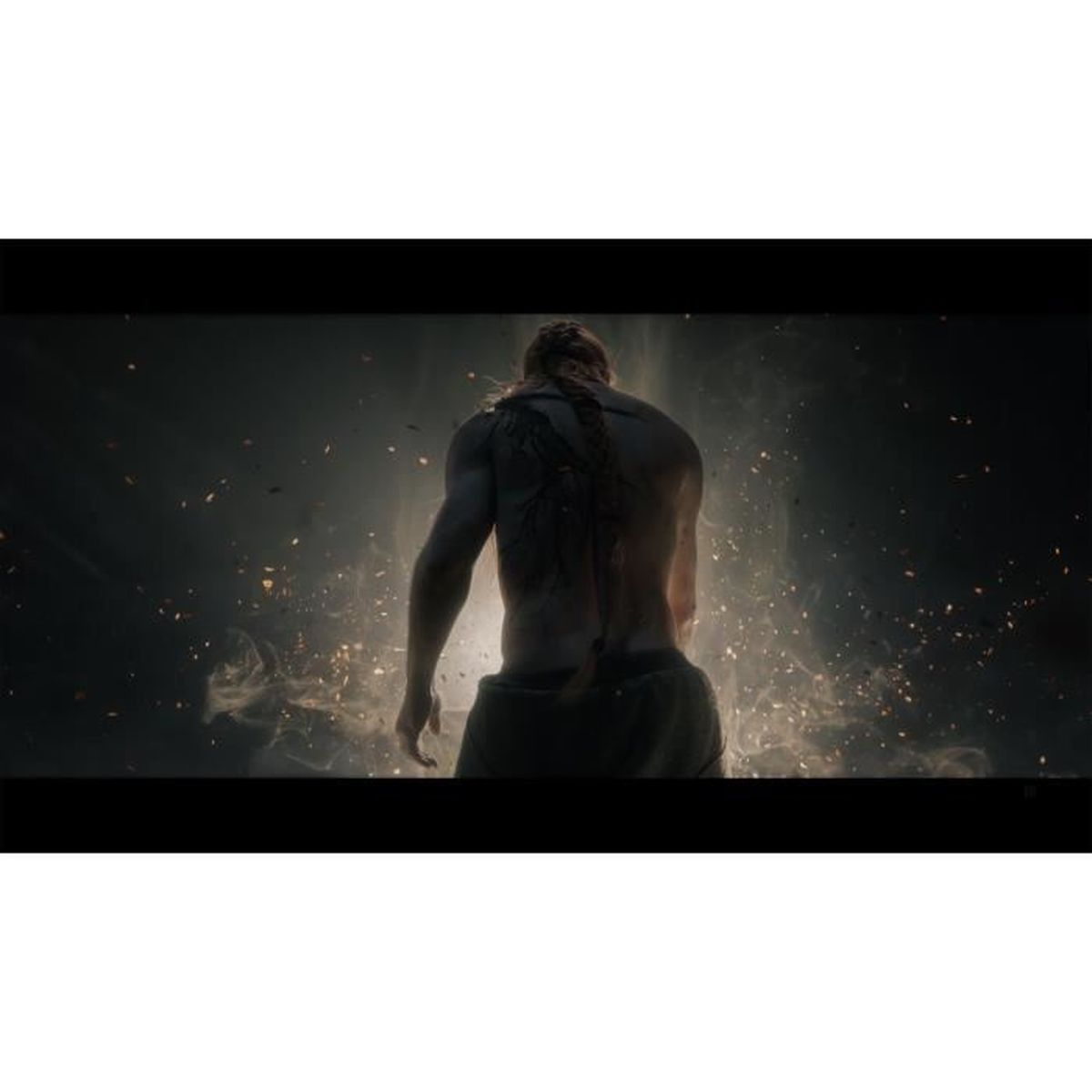 Umięśniony mężczyzna od tyłu, z tatuażem na plecach, stojący przed światłem.