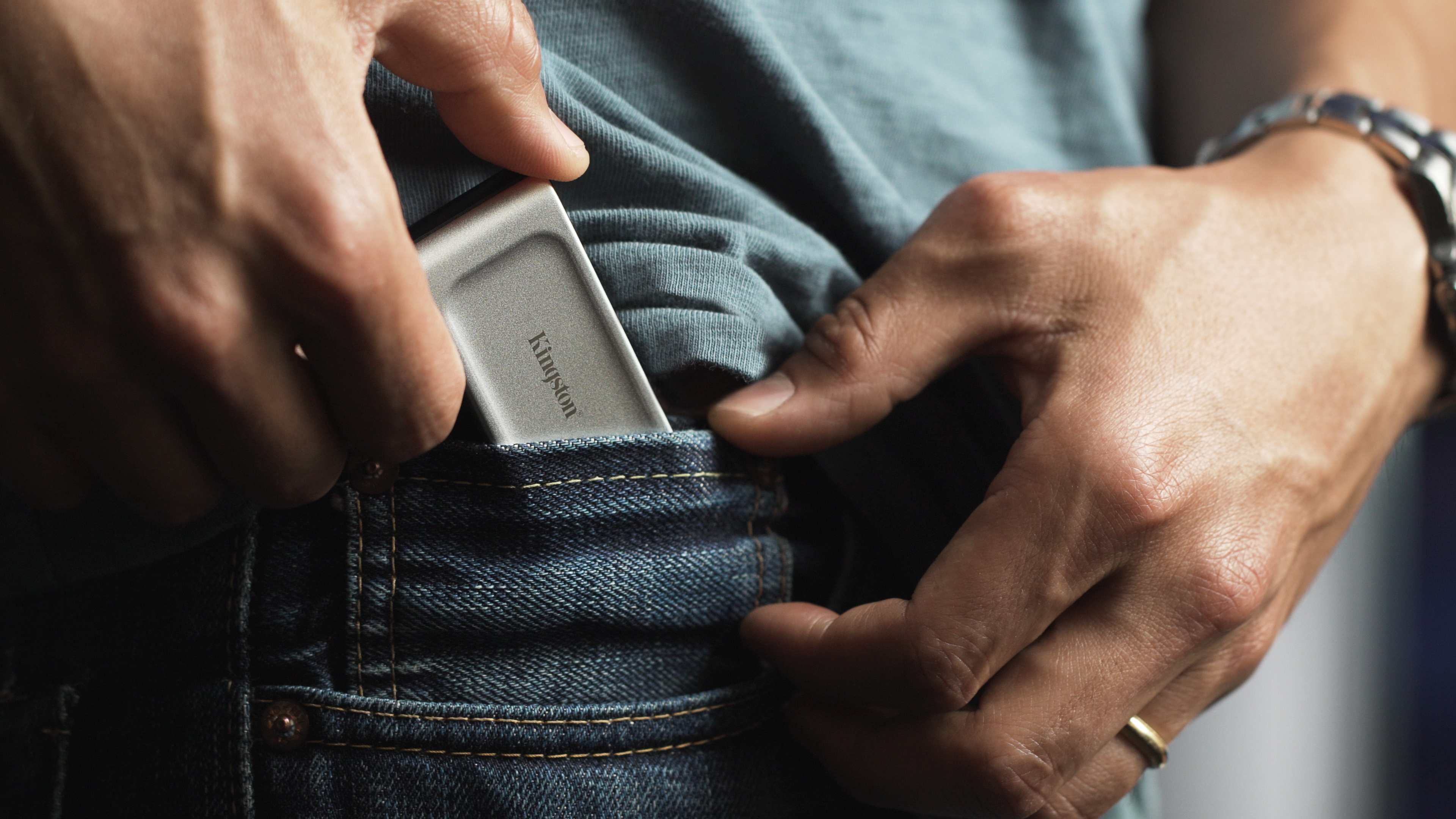 Męskie dłonie wkładają urządzenie Kingston do kieszeni dżinsów.