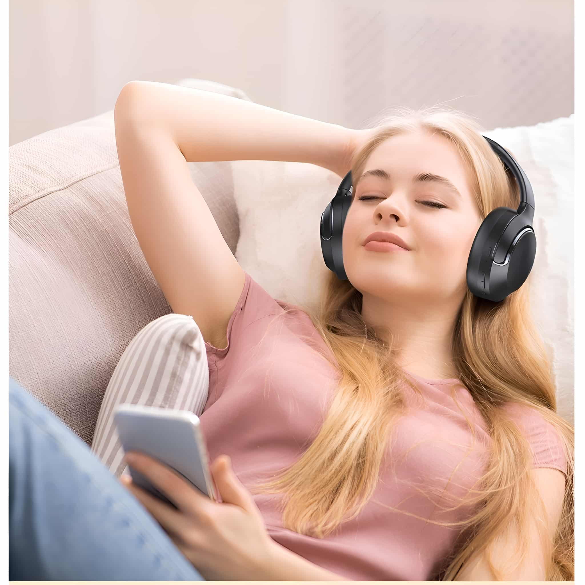 Blonde Frau auf einem Sofa mit Kopfhörern und Handy, Augen geschlossen.