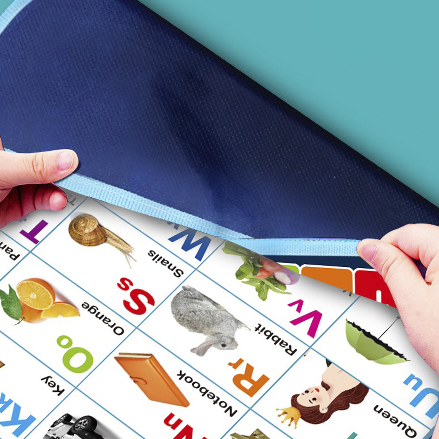Hände ziehen eine blaue Matte zurück und enthüllen eine Alphabet-Tabelle mit Bildern wie Schnecke, Kaninchen und Orange.