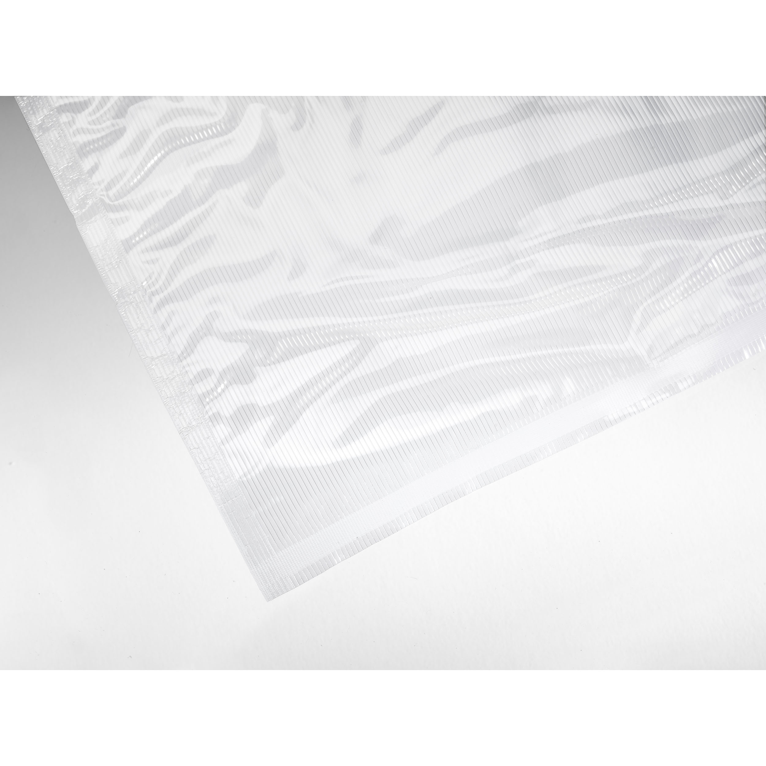 Ein transparenter Vakuumbeutel, teilweise geöffnet, auf einer weißen Oberfläche, mit gerippter Textur.