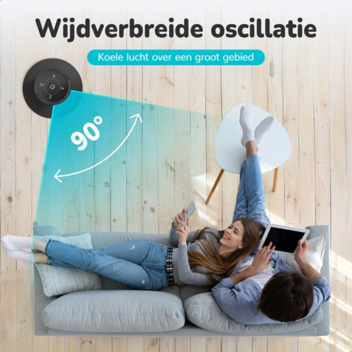 Ein Paar auf einem Sofa mit Ventilator und Tablet.