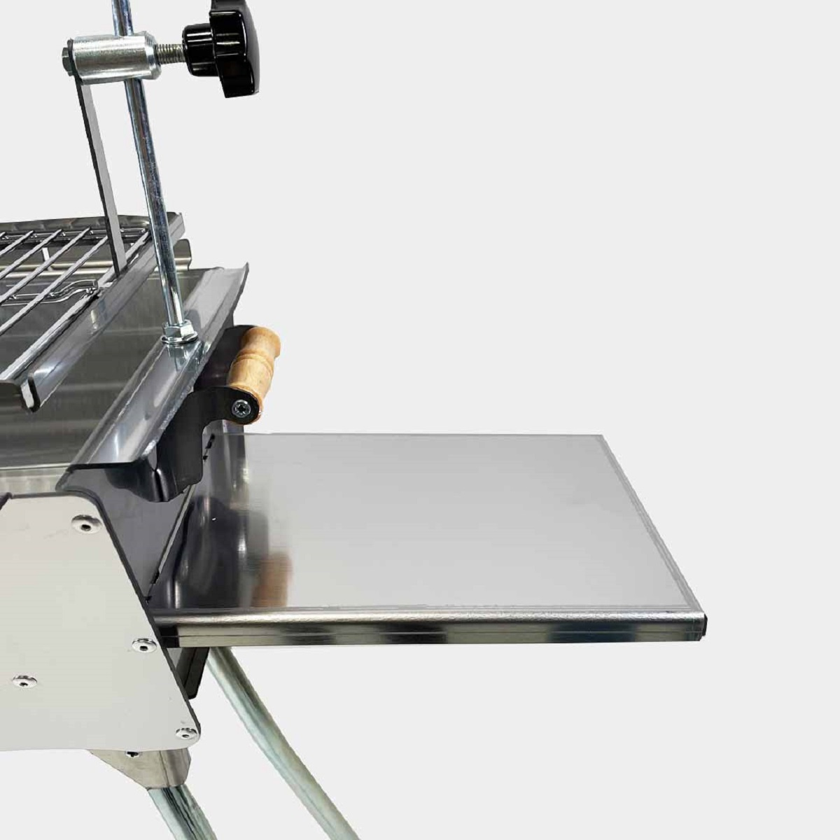 Ein Edelstahlgrill mit Seitenablage. Er hat einen Griff und einen Grillrost.