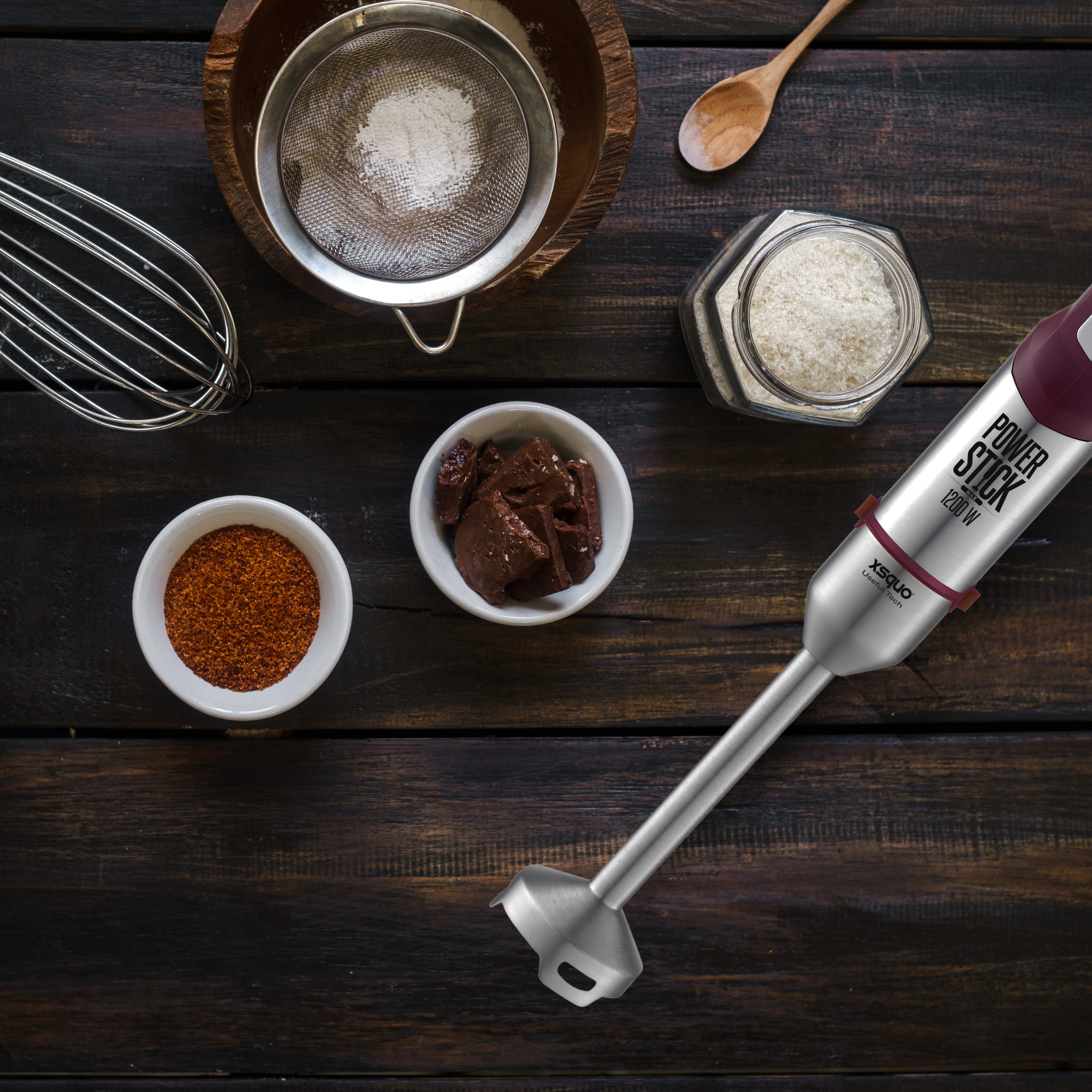 Vista cenital de ingredientes y batidora de mano sobre superficie de madera.