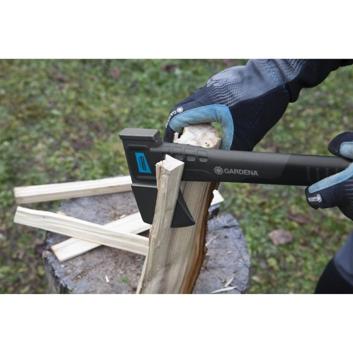 Osoba rąbie drewno siekierą Gardena na pniu. Widoczne rękawice i drewno.