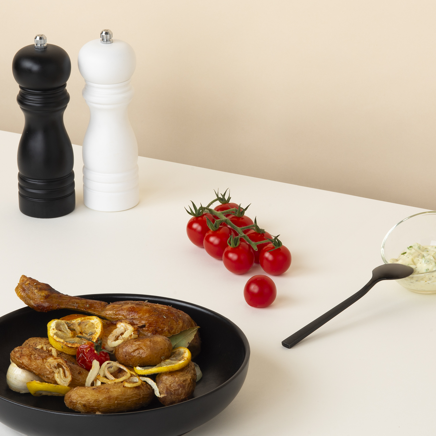 Disposizione di cibo su un tavolo bianco, tra cui pollo arrosto e pomodori.