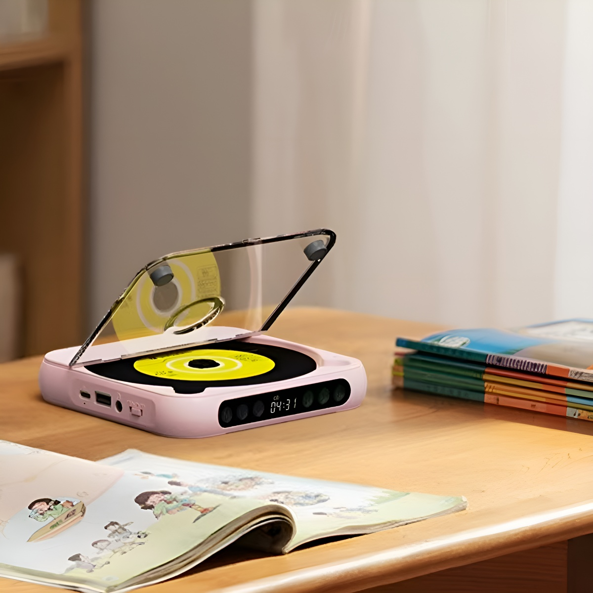 Ein rosa tragbarer CD-Player mit gelber Scheibe. Bücher und eine Seite liegen auf einem Holztisch.