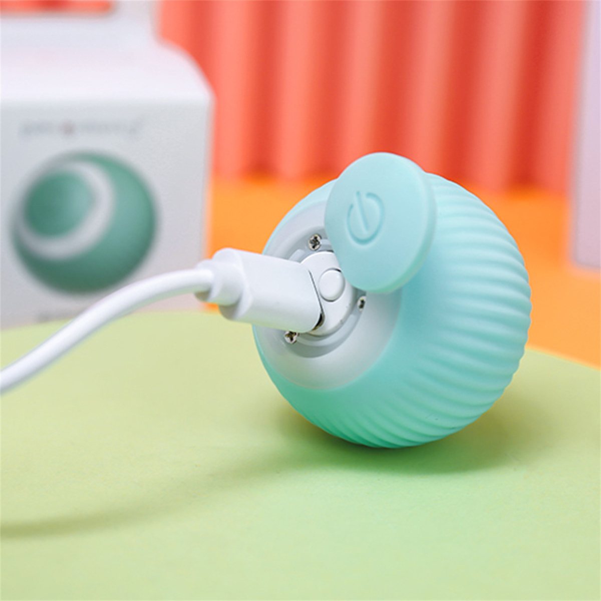 Ein kleines, teal-farbenes Gerät mit einem weißen Ladekabel.