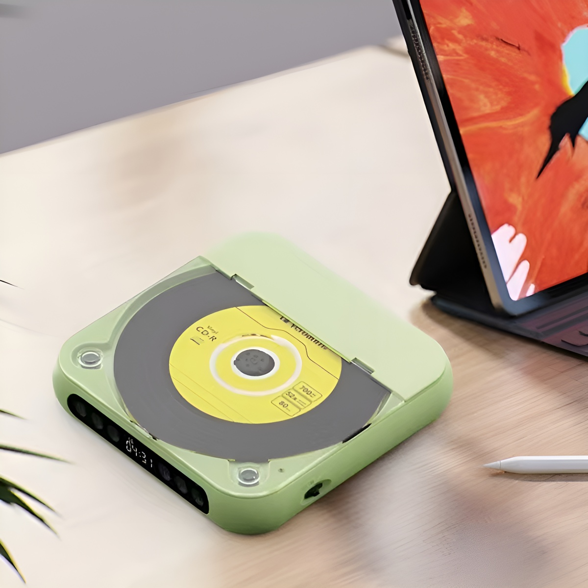 Ein CD-Player mit grünem Gehäuse, einer CD und einem Tablet.