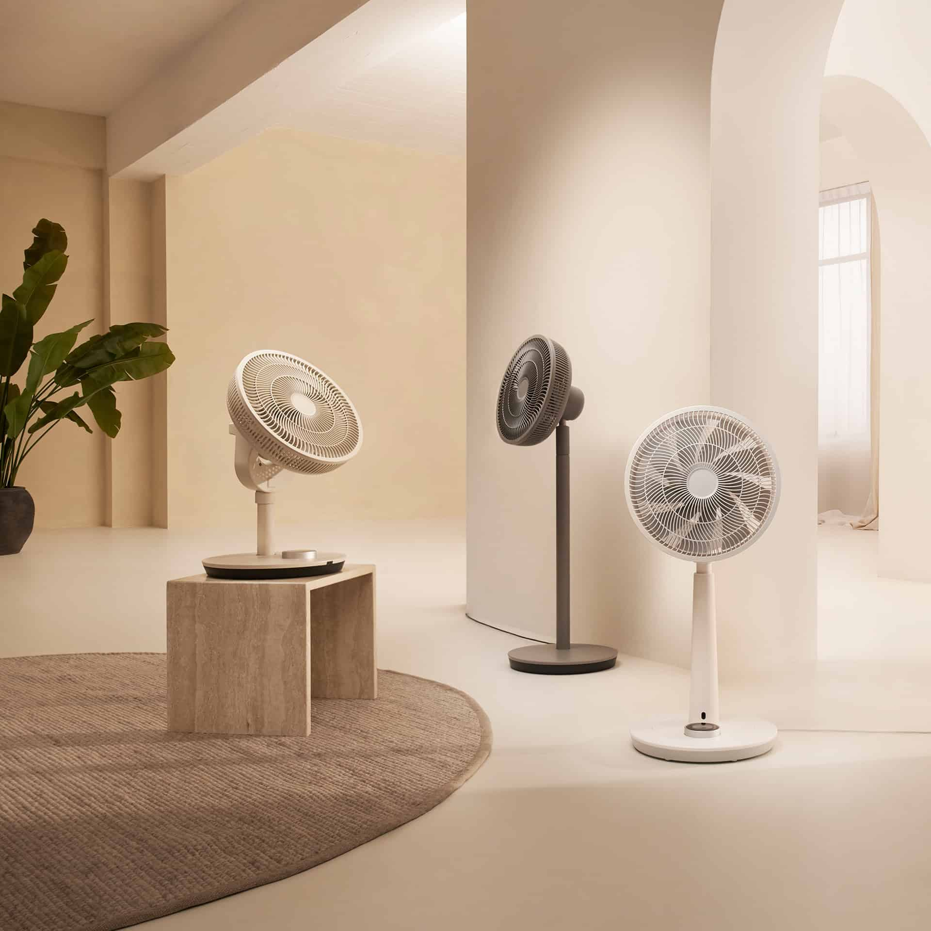 Drei moderne Ventilatoren in einem Raum, einer auf einem Tisch, einer auf einem Ständer.
