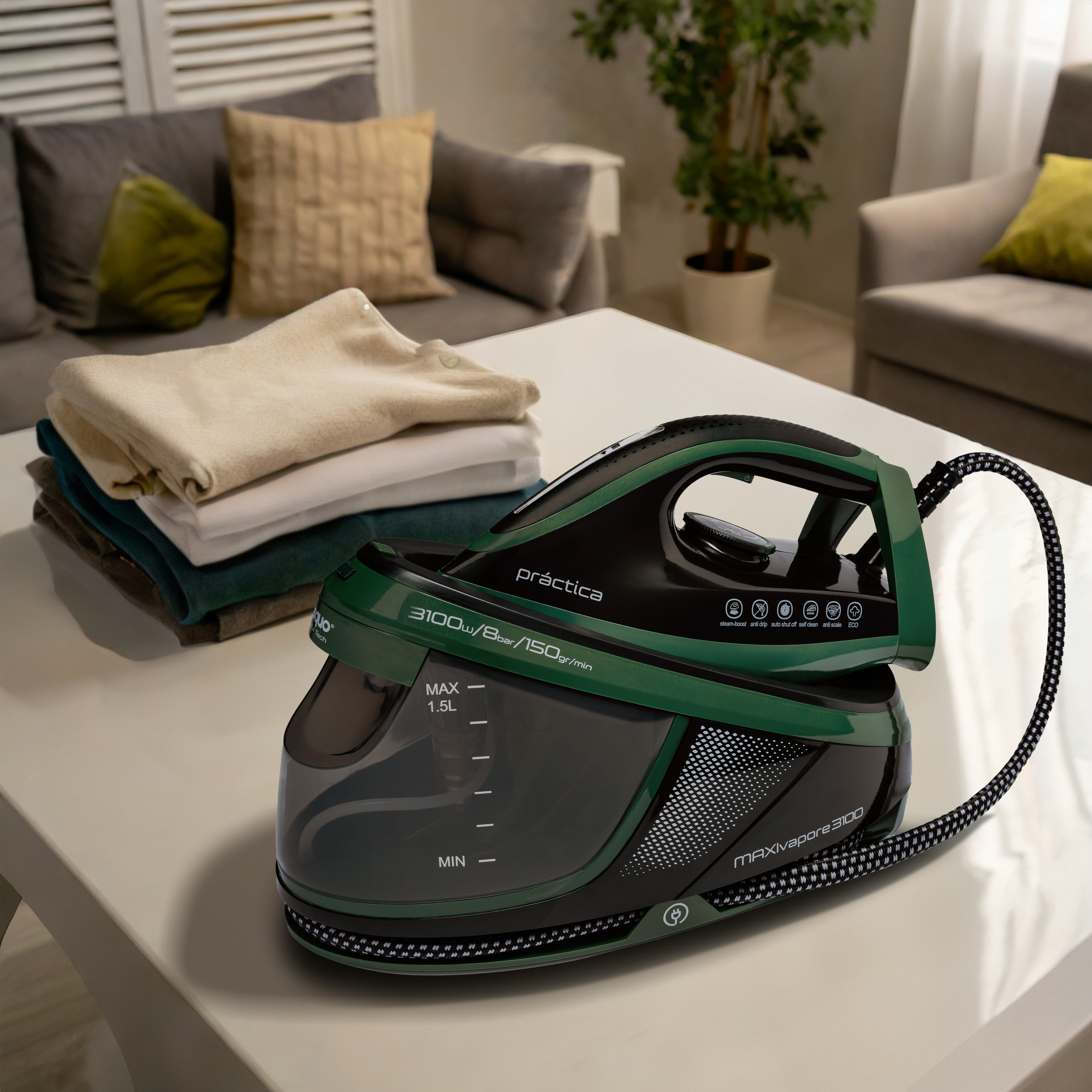 Una plancha verde y negra sobre una mesa blanca con ropa al fondo.