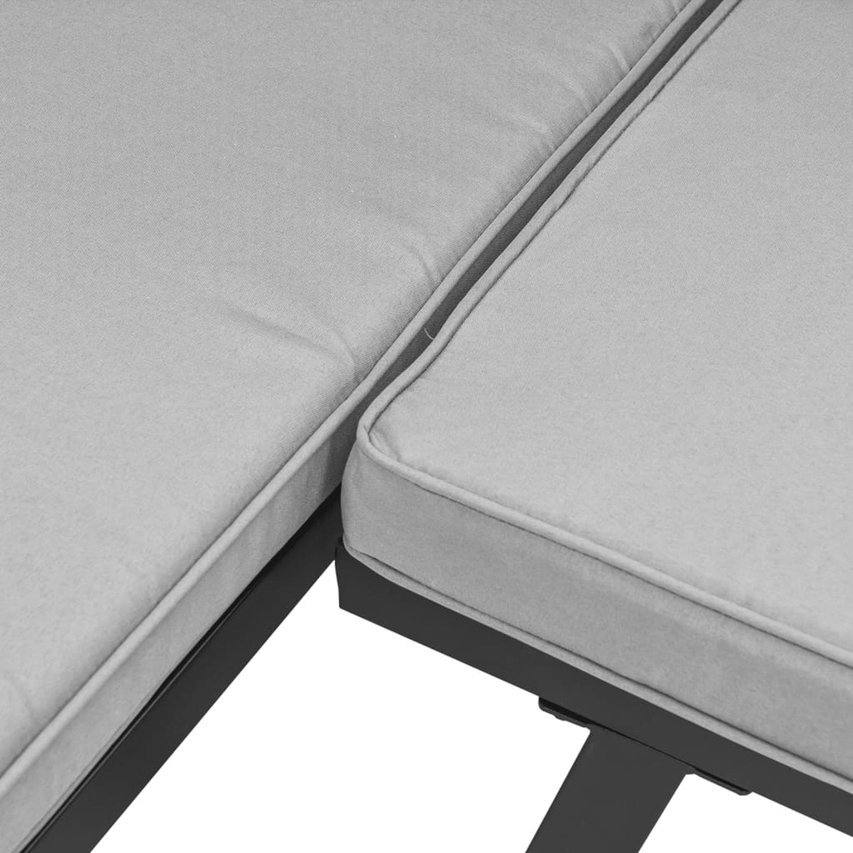 Primo piano di una chaise longue da esterno imbottita grigio chiaro. Cornice nera. Sfondo bianco.