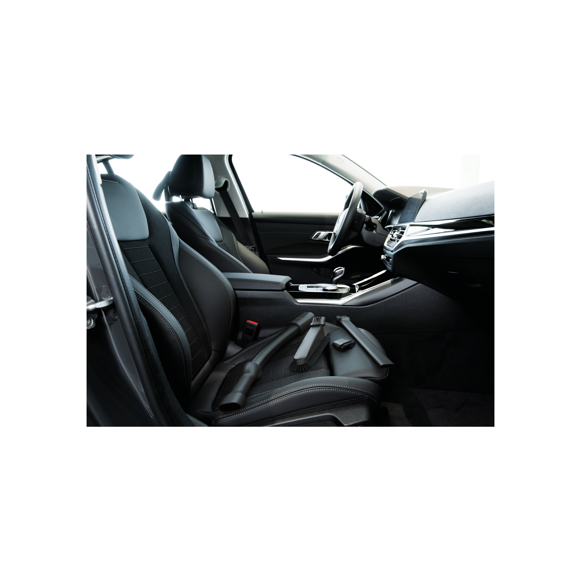 Interior de coche con asientos de cuero negro. Herramientas de aspiración en el asiento trasero.