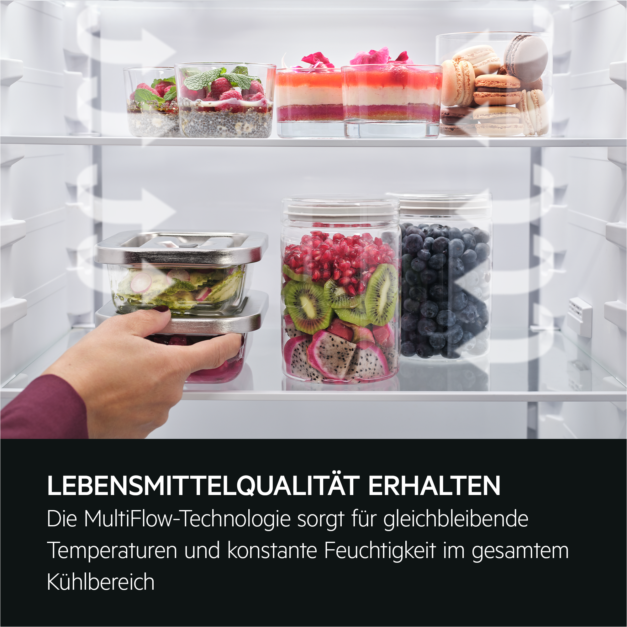 Kühlschrankinnenraum mit verschiedenen Lebensmitteln in Glasbehältern. Hand greift nach einem Behälter.