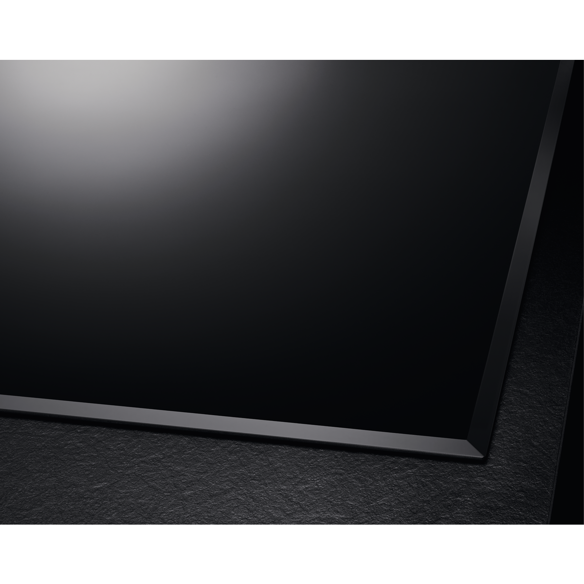 Piano cottura nero con cornice nera. Il piano cottura è liscio e lucido. La superficie riflette la luce.
