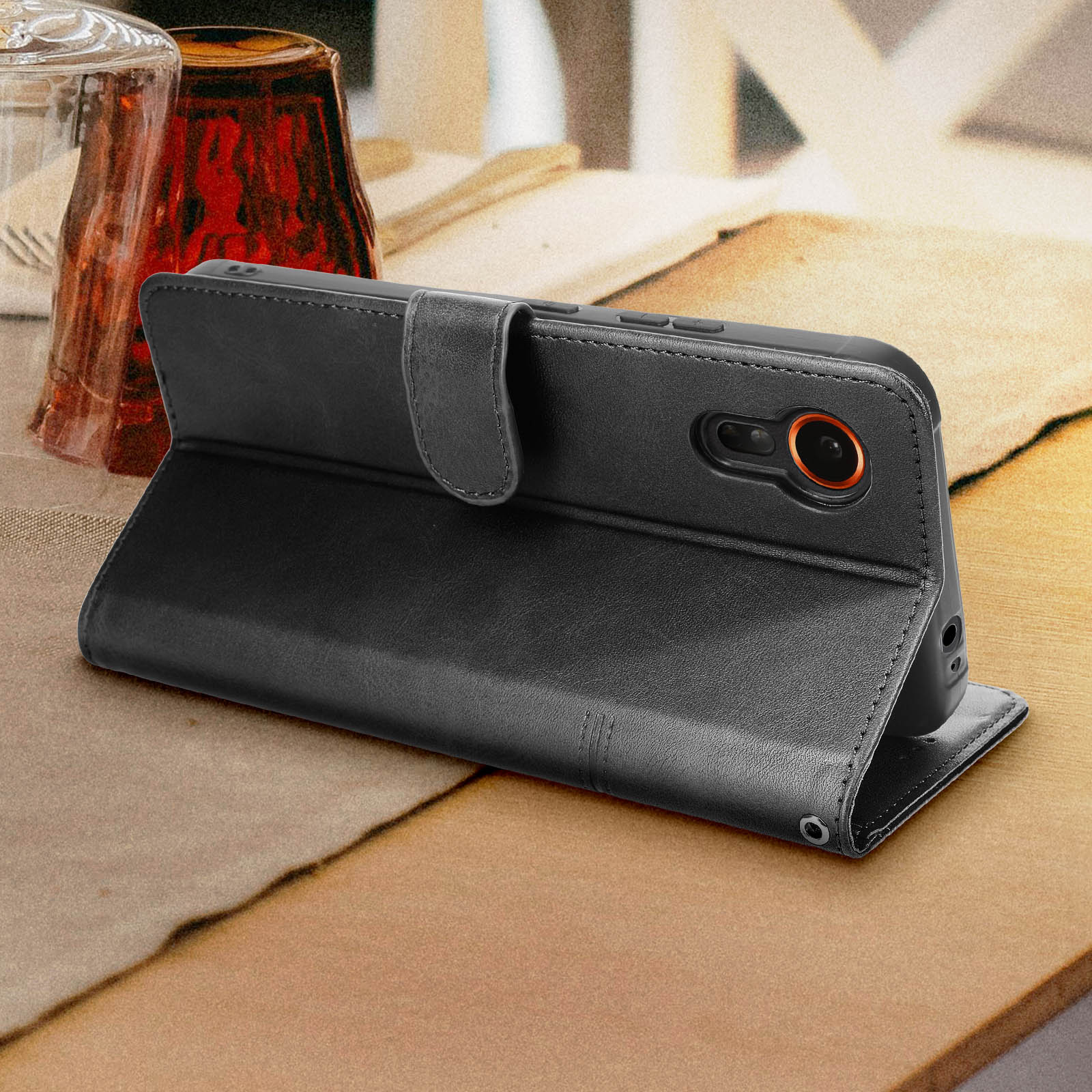 Eine schwarze Leder-Handyhülle ist geöffnet und zeigt ein Telefon, das auf einer Holzoberfläche liegt.