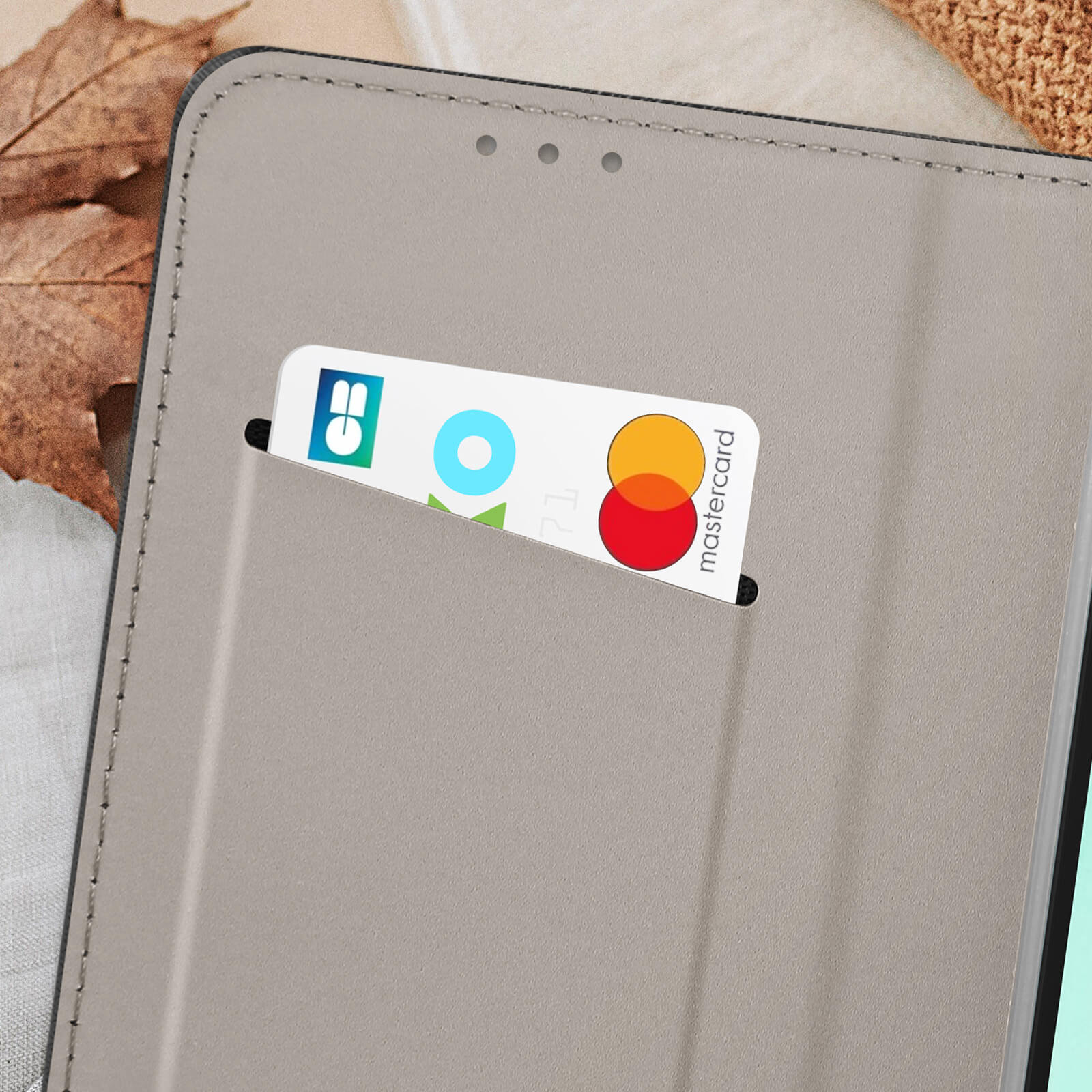 Primo piano di una custodia grigia per telefono con una carta nello slot. La carta ha un logo Mastercard.