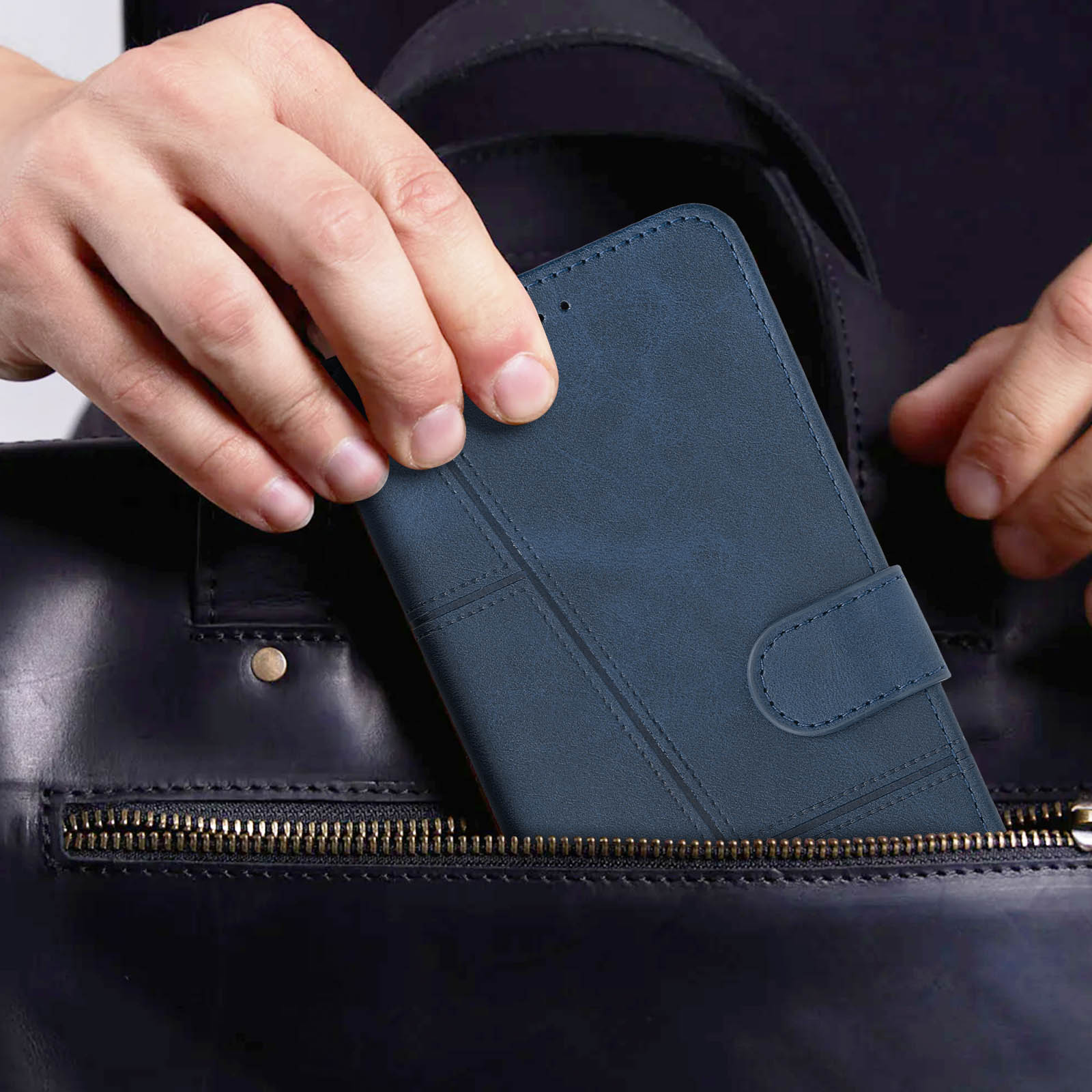 Eine Hand steckt eine blaue Handytasche in eine schwarze Handtasche.