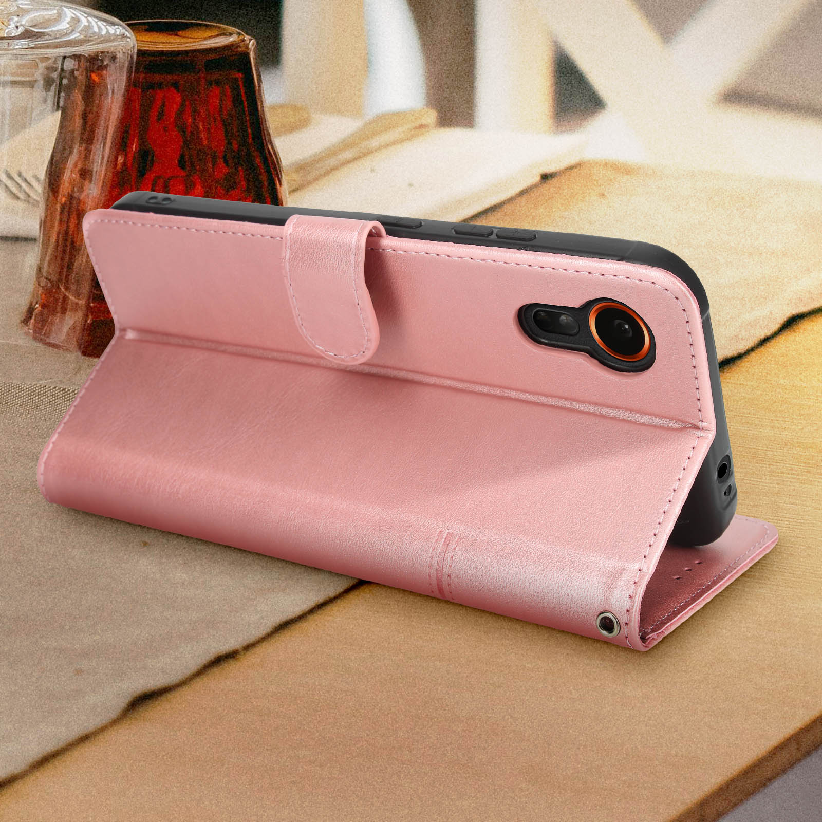 Eine rosa Handyhülle, die sich öffnet, um ein Smartphone zu zeigen. Die Hülle befindet sich auf einer gemusterten Oberfläche.
