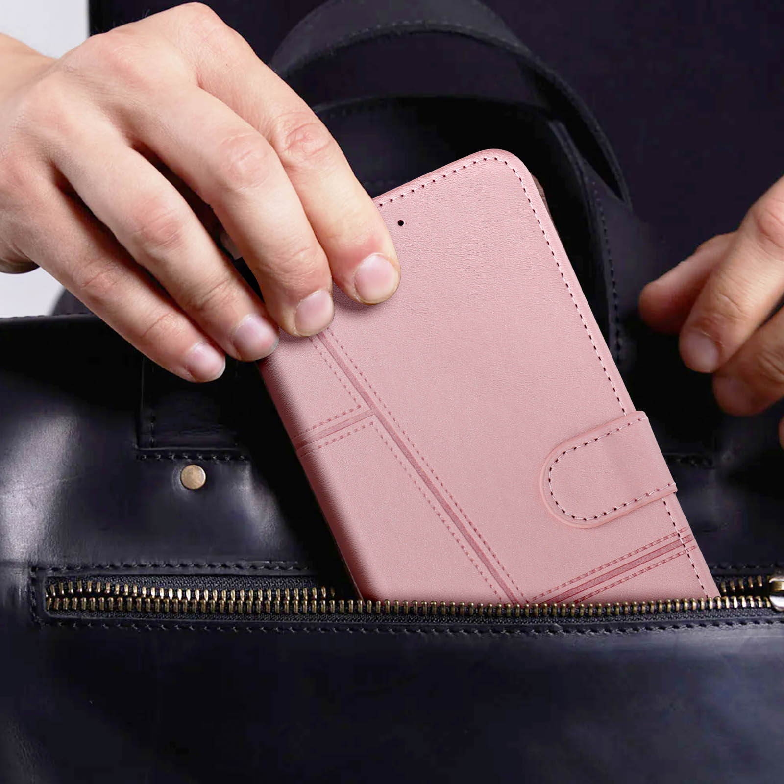 Hände einer Person, die ein rosa Portemonnaie in eine schwarze Ledertasche legen.