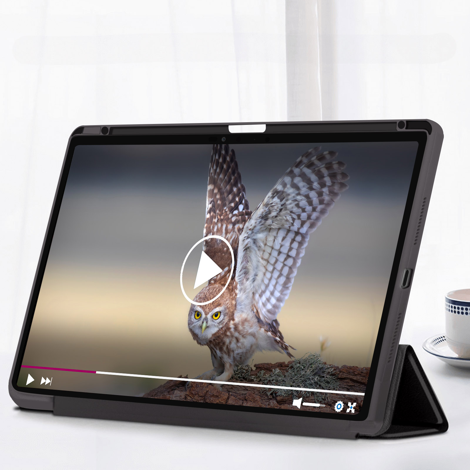 Tablet che mostra un video di un uccello. Tavolo bianco e una tazza sullo sfondo.