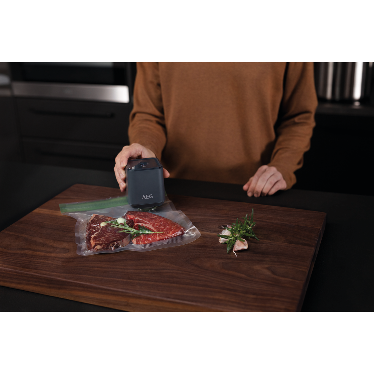 Una persona usa una selladora al vacío para sellar una bolsa de carne en una tabla de cortar de madera.