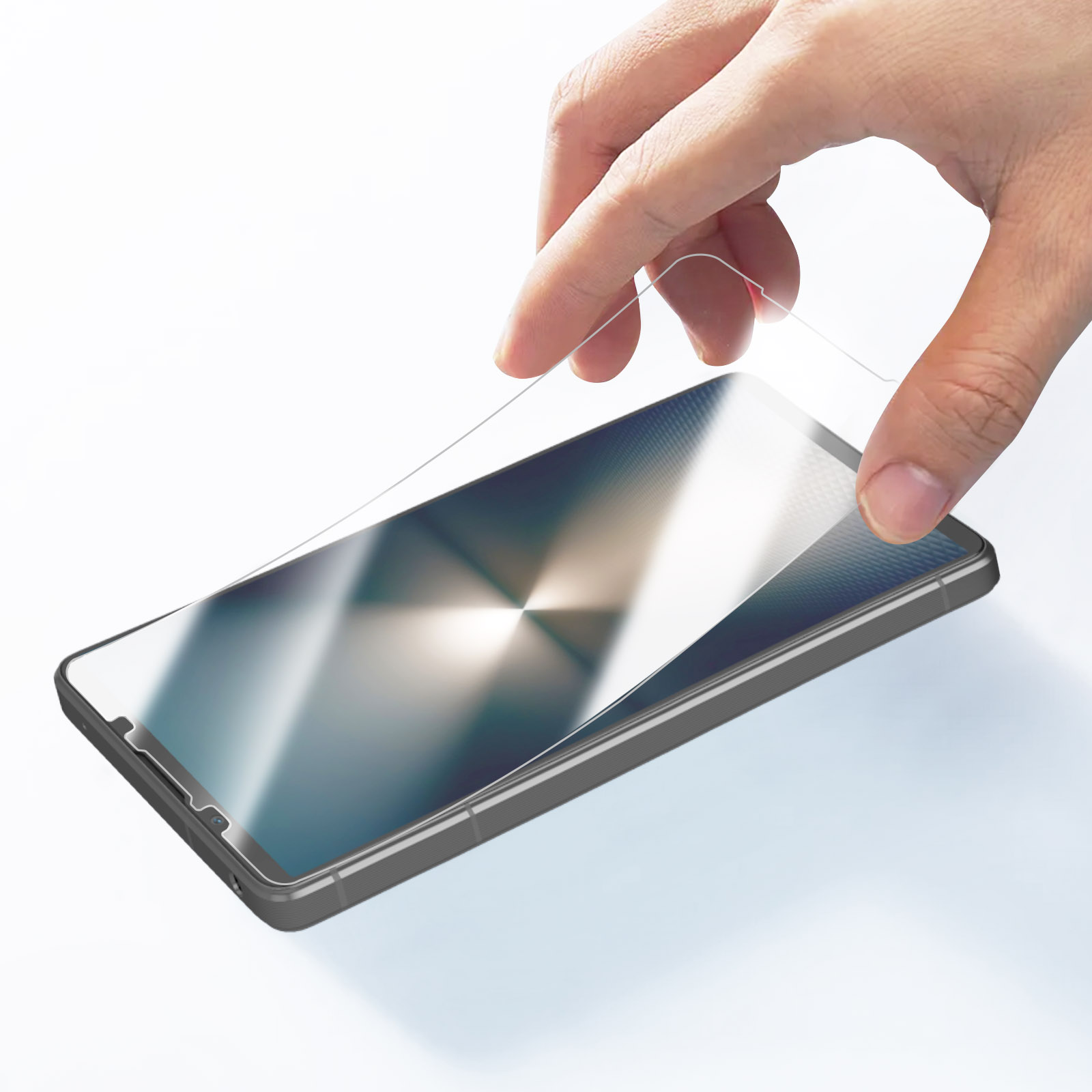 Una mano che tiene una protezione per lo schermo sopra uno smartphone nero.
