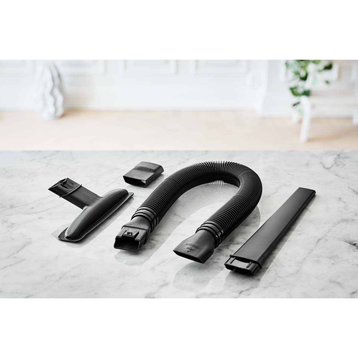 Zestaw czarnych nasadek do odkurzacza, na białej marmurowej powierzchni.